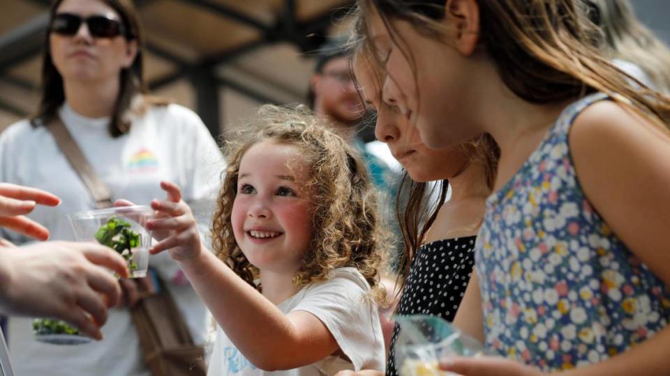 From left, Harvest Nolan, 6, Opal Quick, 6, and Rosie Quick, 7, smell herbs at the Power of Produce booth at the Lexington Farmers Market on Saturday, June 24, 2023 at Fifth Third Pavilion in Lexington, Ky.