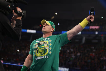 John Cena holding a mic out to the crowd while standing in the ring