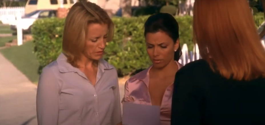 Felicity Huffman, Eva Longoria, and Marcia Cross stand outdoors, looking at a sheet of paper with serious expressions. 
