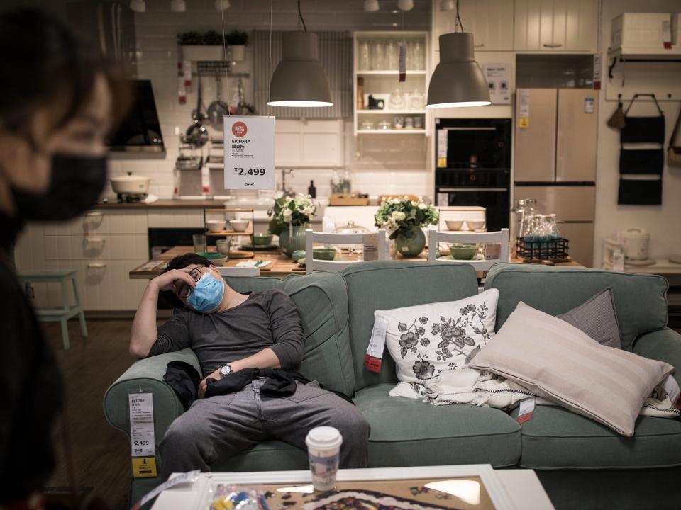 A man sleeping on a green sofa in an IKEA store showroom in Wuhan, China.