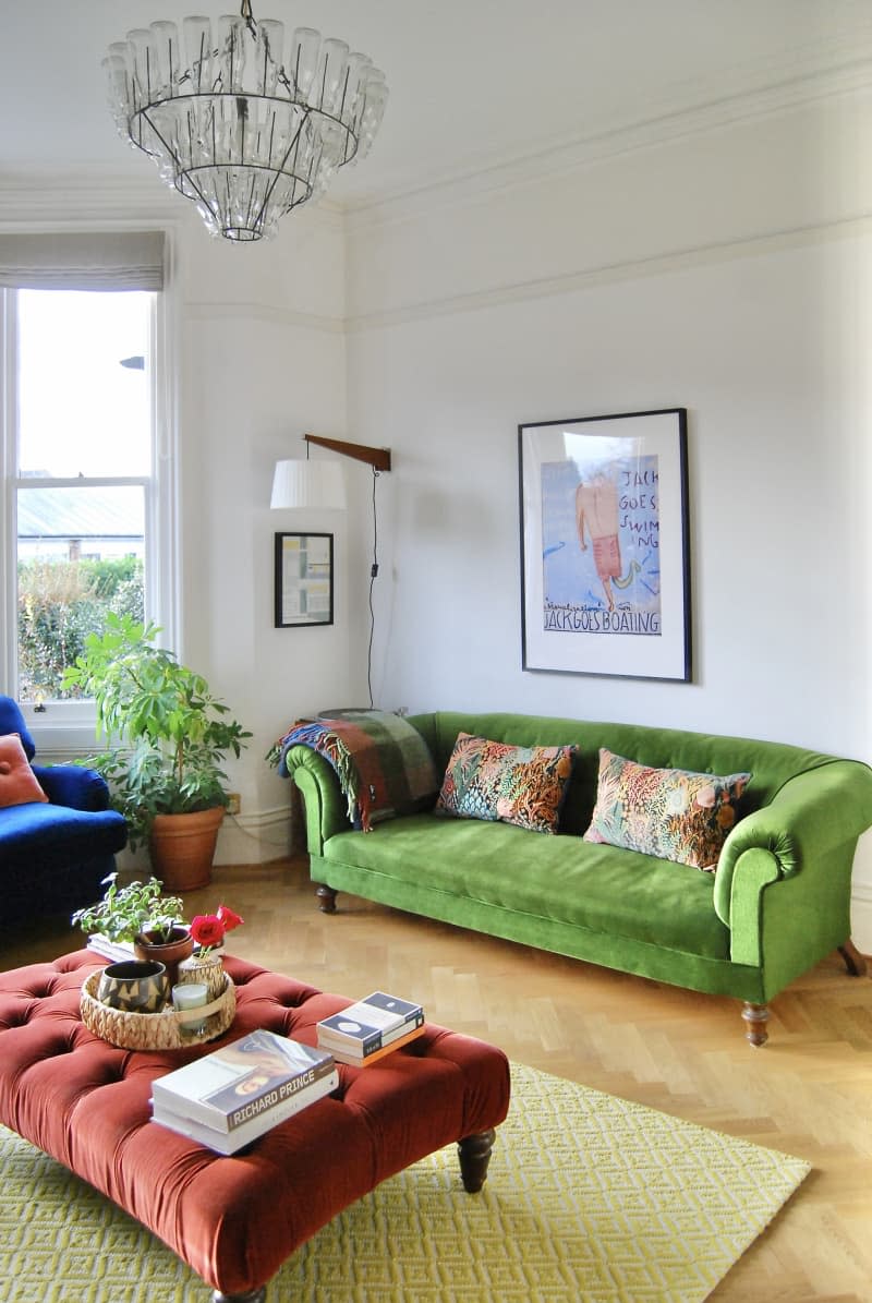 Living room with green velvet couch flanked by matching blue love seat and red ottoman.