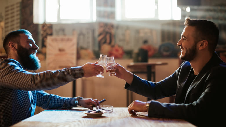 two friends toasting bourbon glasses