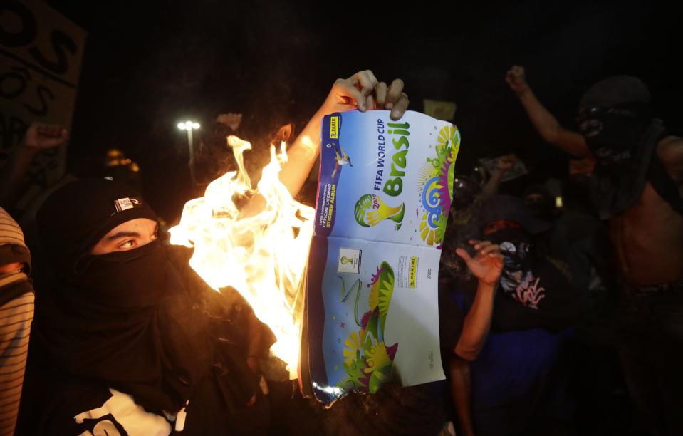 Demonstrators burn a 2014 World Cup sticker album during a protest against the 2014 World Cup in Rio de Janeiro