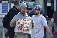 Justin Paetow, who works in the tin shop at Bath Iron Works, demonstrates against COVID-19 vaccine mandate outside the shipyard on Friday, Oct. 22, 2021, in Bath, Maine. Some American workers are making the painful decision to quit their jobs and abandon cherished careers in defiance of what they consider intrusive mandates requiring all businesses with 100 or more workers require employees to be fully vaccinated or undergo weekly testing. (AP Photo/Josh Reynolds)