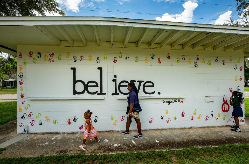 From left, Ruby Amos, her sister Jaleah Amos and their cousin, Aubrey Amos, stand along a mural on a building at Spence Park In Mulberry. They are part of a nonprofit organization, Inspired Ambitious Young Believers, that planned and painted the "believe" message on the wall. The group previously sponsored a mural painted on the other side of the building by Gabriela Jaxon of Lakeland.