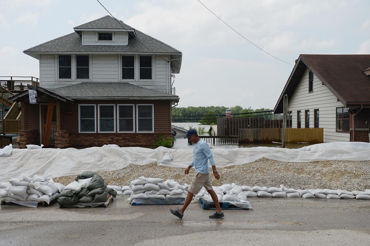 A man walks along a levee as floodwaters rise on June 7, 2019 in Grafton, Illinois.