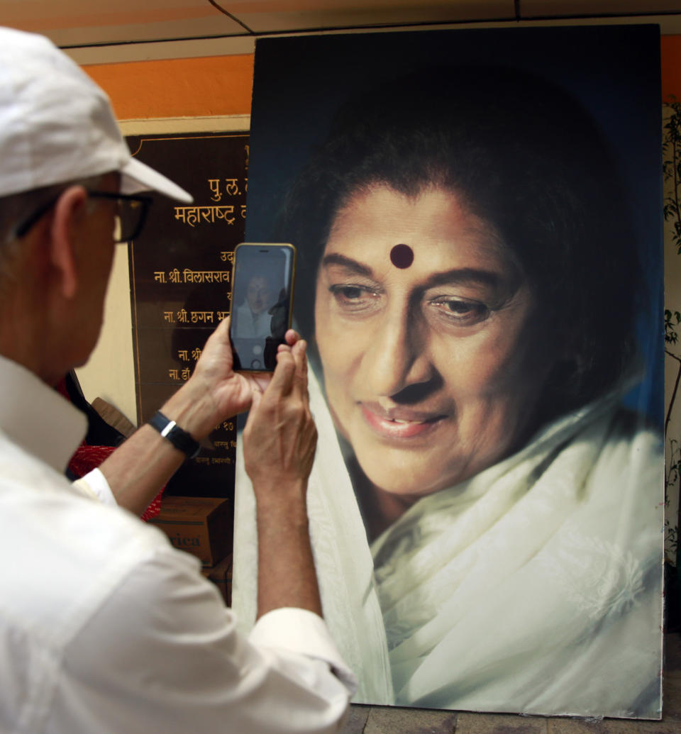 A man takes a photograph of a giant portrait of Indian musician Kishori Amonkar in Mumbai, India, Tuesday, April 4, 2017. Amonkar, renowned for her innovative interpretation of classical Indian music, has died, one of her students said Tuesday. She was 84. (AP Photo/Rafiq Maqbool)