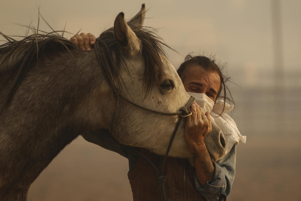 Fabio Losurdo comforts his horse, Smarty, at a ranch in Simi Valley, Calif., Wednesday, Oct. 30, 2019. A brush fire broke out just before dawn in the Simi Valley area north of Los Angeles. (AP Photo/Ringo H.W. Chiu)