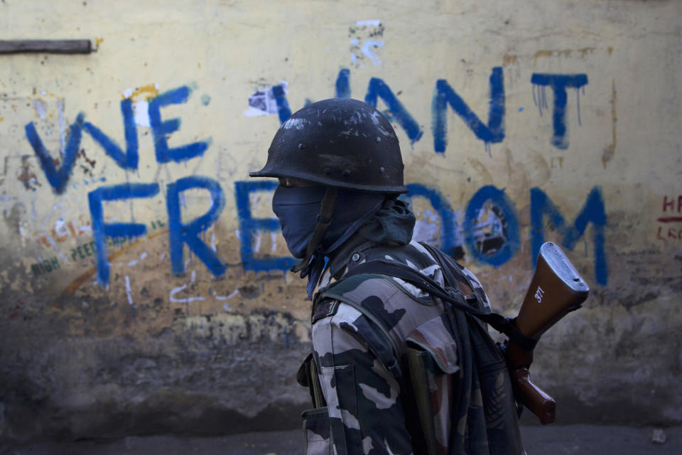 FILE- In this Aug. 29, 2016 file photo, an Indian paramilitary soldier walks past graffiti on a wall in Srinagar, Indian-controlled Kashmir. As India considers its response to the suicide car bombing of a paramilitary convoy in Kashmir that killed dozens of soldiers on Feb. 14, 2019, a retired military commander who oversaw a much-lauded military strike against neighboring Pakistan in 2016 has urged caution. India blamed the attack on Pakistan and promised a "crushing response." New Delhi accuses its archrival of supporting rebels in Kashmir, a charge that Islamabad denies. (AP Photo/Dar Yasin, File)