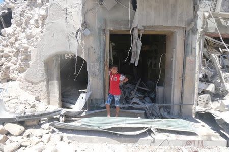 A boy stands at a site hit by a barrel bomb in the rebel held area of Old Aleppo, Syria July 11, 2016. REUTERS/Abdalrhman Ismail - RTSHDMV