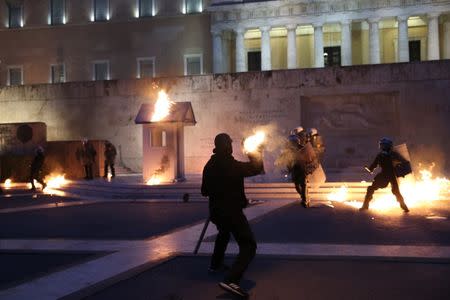 A masked demonstrator throws a petrol bomb to riot police outside the parliament building as Greek lawmakers vote on the latest round of austerity Greece has agreed with its lenders, in Athens, Greece, May 18, 2017. REUTERS/Costas Baltas