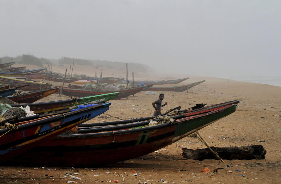 An Indian fisherman runs between the docked fishing boats amid strong winds at Chandrabhaga beach in Puri district of eastern Odisha state, India, Thursday, May 2, 2019. Hundreds of thousands of people were evacuated along India's eastern coast on Thursday as authorities braced for a cyclone moving through the Bay of Bengal that was forecast to bring extremely severe wind and rain. (AP Photo)
