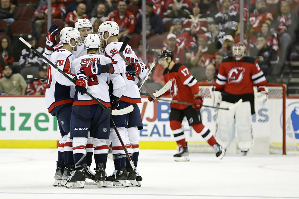Washington Capitals defenseman Nick Jensen (3) celebrates with teammates after scoring a goal past New Jersey Devils goaltender Mackenzie Blackwood, back right, in the second period of an NHL hockey game Monday, Oct. 24, 2022, in Newark, N.J. (AP Photo/Adam Hunger)