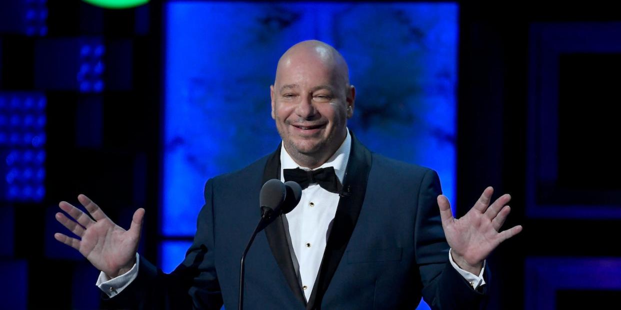 Jeff Ross onstage in a tuxedo, standing with arms spread during a 2019 Comedy Central roast of Alec Baldwin