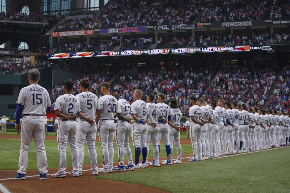 FILE - The Texas Rangers stand for the national anthem before an opening day baseball game against the Philadelphia Phillies, March 30, 2023, in Arlington, Texas. The Texas Rangers are the only one of the 30 MLB teams that aren't hosting Pride Night during a game in June as part of Pride Month. (AP Photo/Jeffrey McWhorter, File)