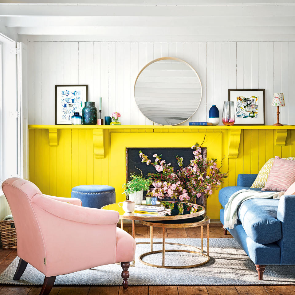 white and yellow living room with pink armchair and blue sofa