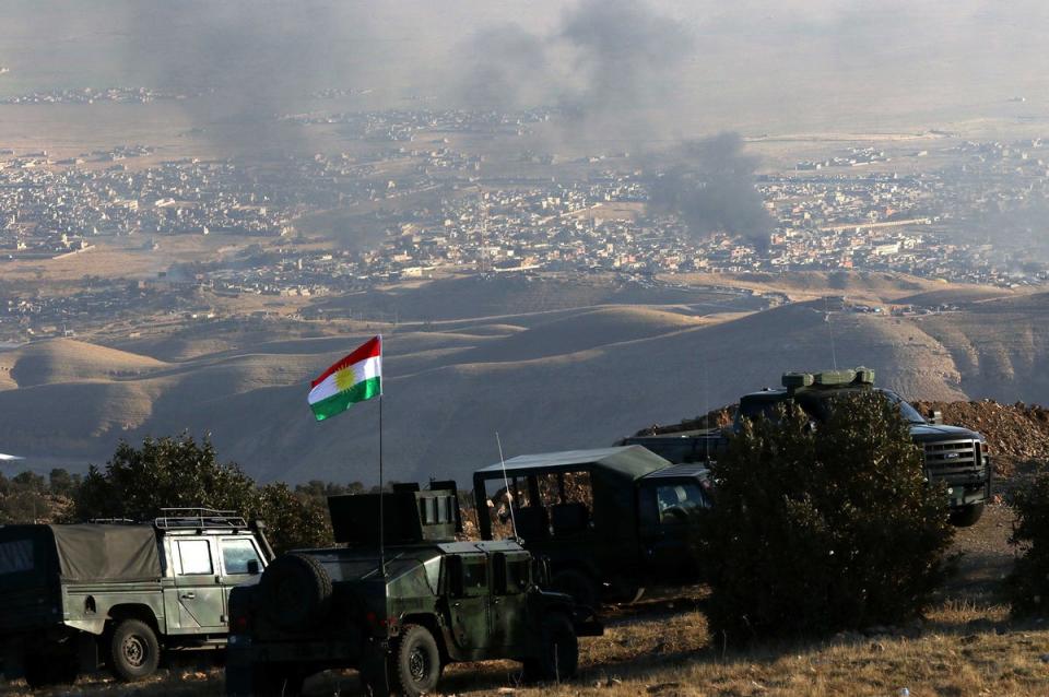 Kurdish forces are stationed on a hill above the town of Sinjar as smoke rises following US airstrikes on 12 November 2015 (AFP/Getty)