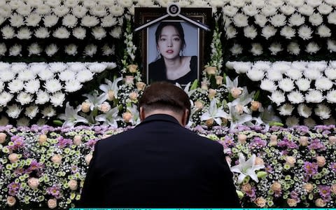 A South Korean man pays tribute at a memorial altar as his makes a call of condolence in honor of the K-pop star Goo Hara at the Seoul St. Mary's Hospital  - Credit: Getty