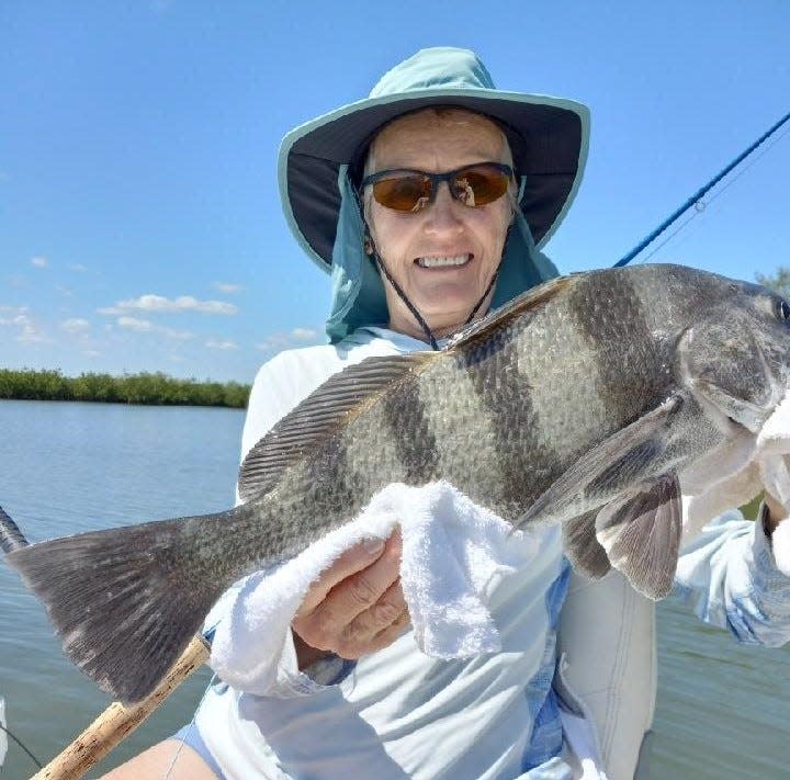 Gayle Giza, Geno's wife, shows off a black drum she brought in on a shrimp fly.
