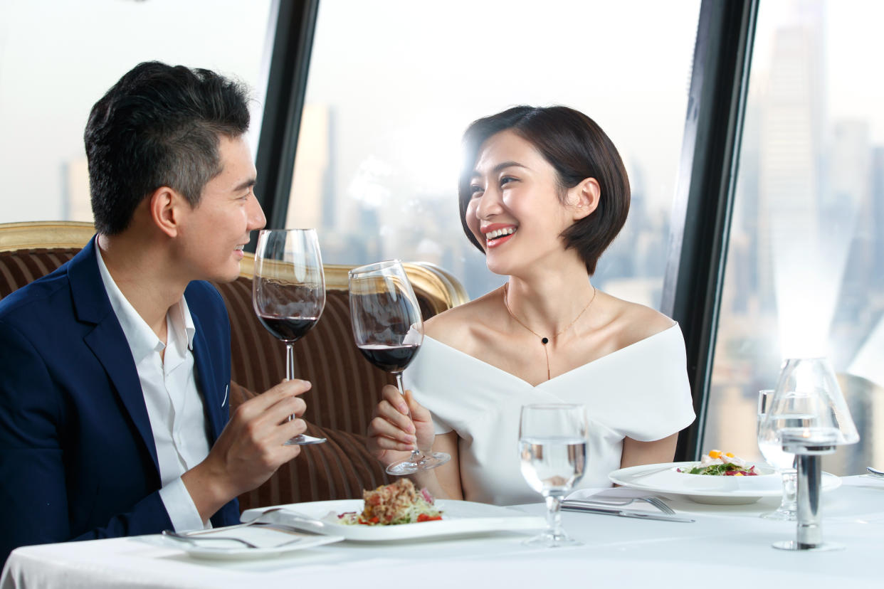 A beautiful young Asian couple enjoying dinner and drinking wine during a date.