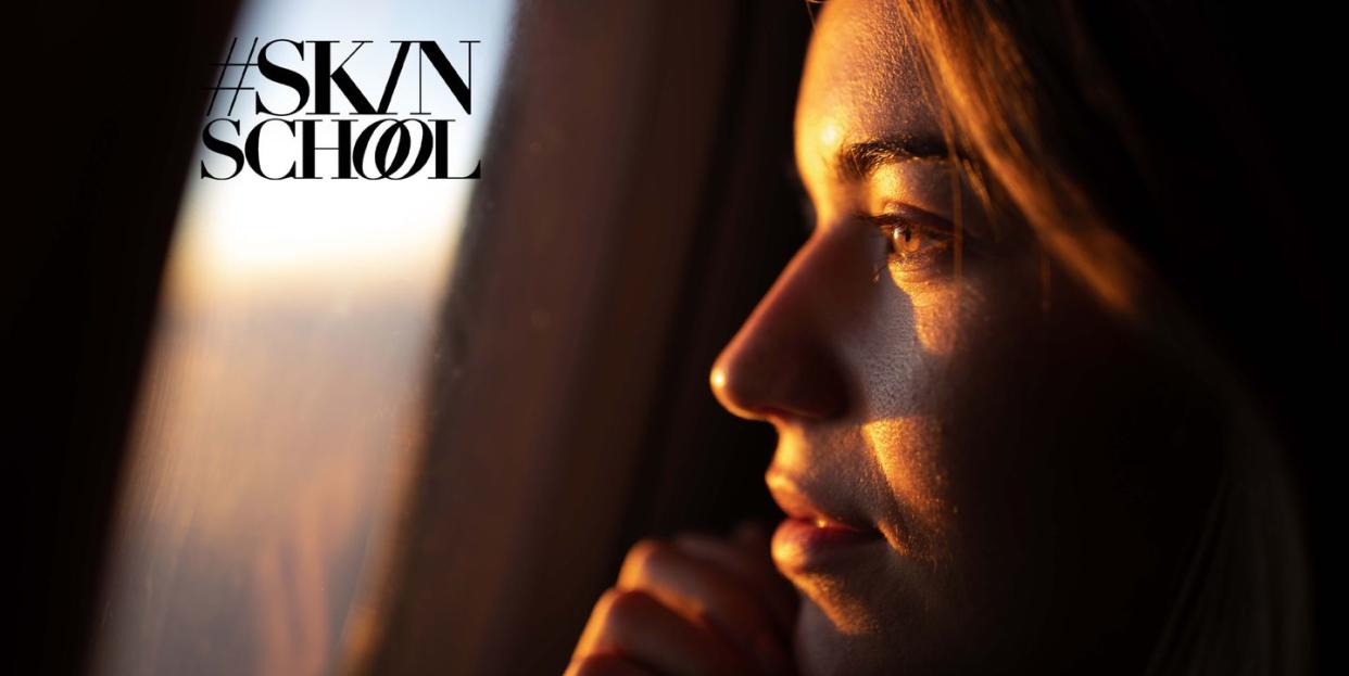 close up of young woman day dreaming while looking through an airplane window at sunset