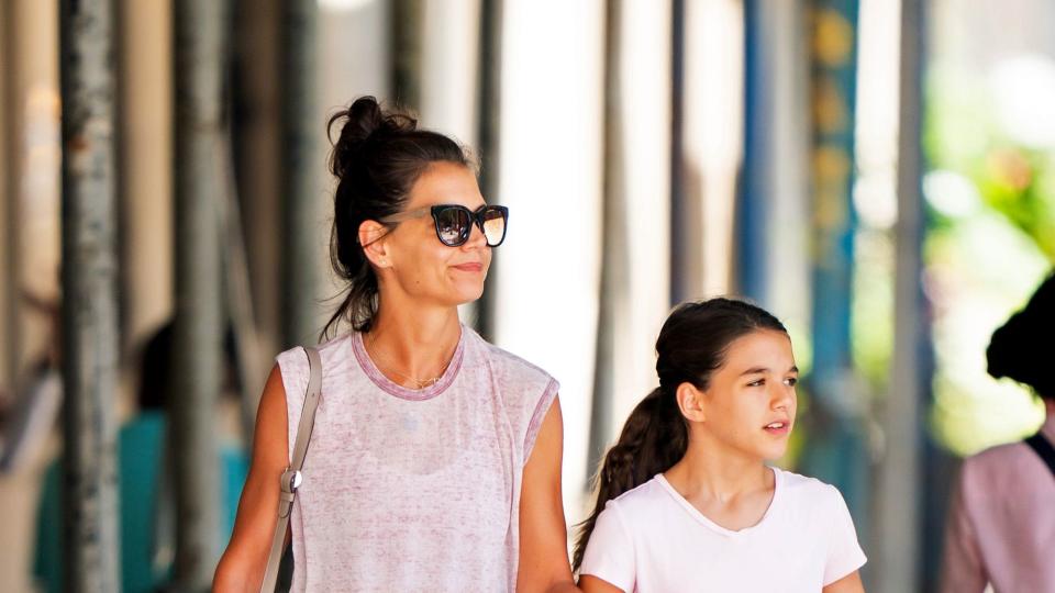 katie holmes and daughter suri cruise walk on a sidewalk, both wear t shirts and holmes has on sunglasses