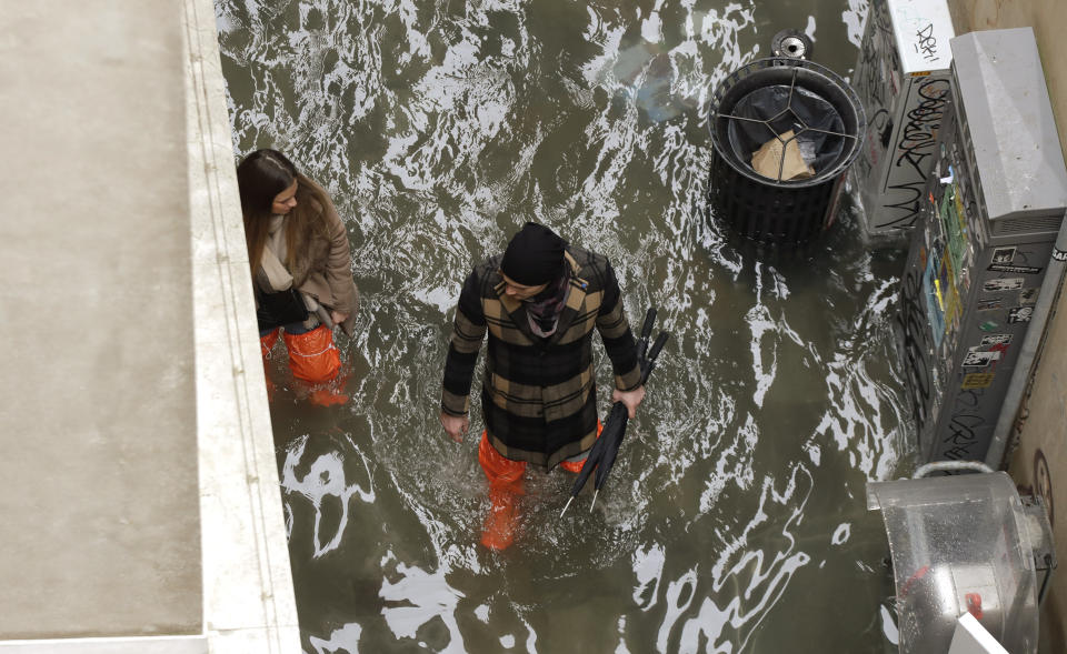 A couple walk in a flooded street of Venice, Italy, Sunday, Nov. 17, 2019. Venetians are bracing for the prospect of another exceptional tide in a season that is setting new records. Officials are forecasting a 1.6 meter (5 feet, 2 inches) surge of water Sunday through the lagoon city. (AP Photo/Luca Bruno)