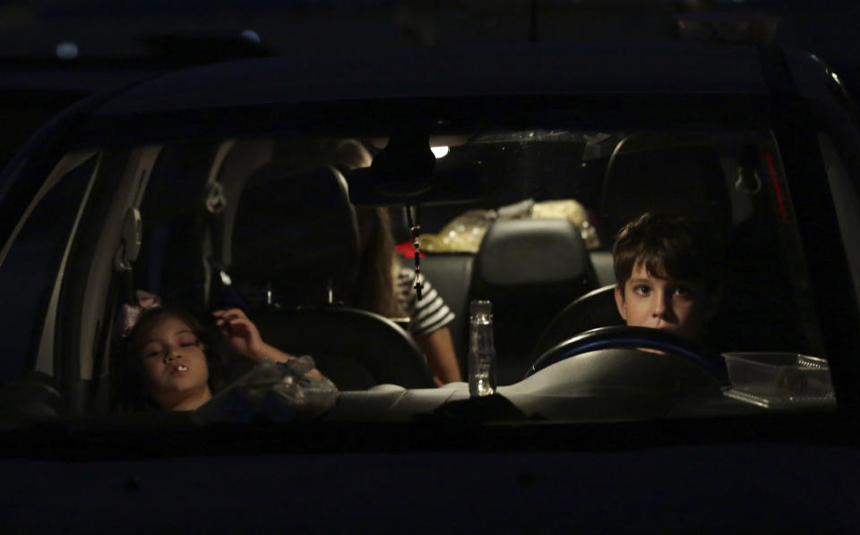 Niños miran una película en un autocine en Brasilia, 23 de mayo de 2020. (AP Foto/Eraldo Peres)