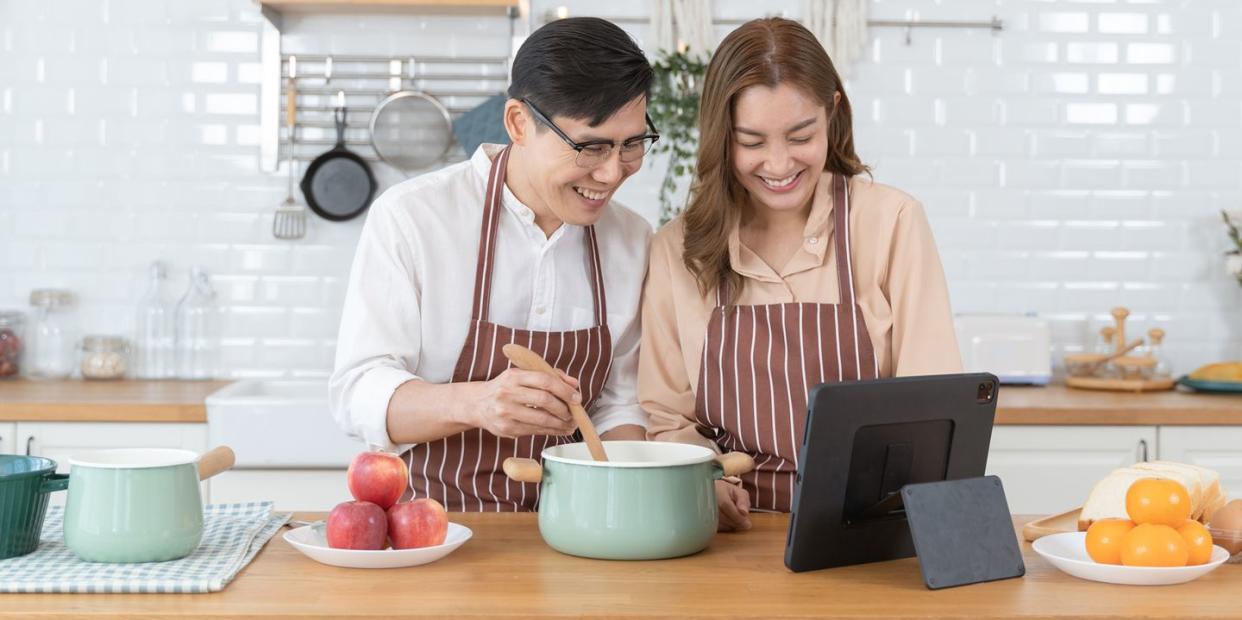 couple in aprons doing a virtual cooking class