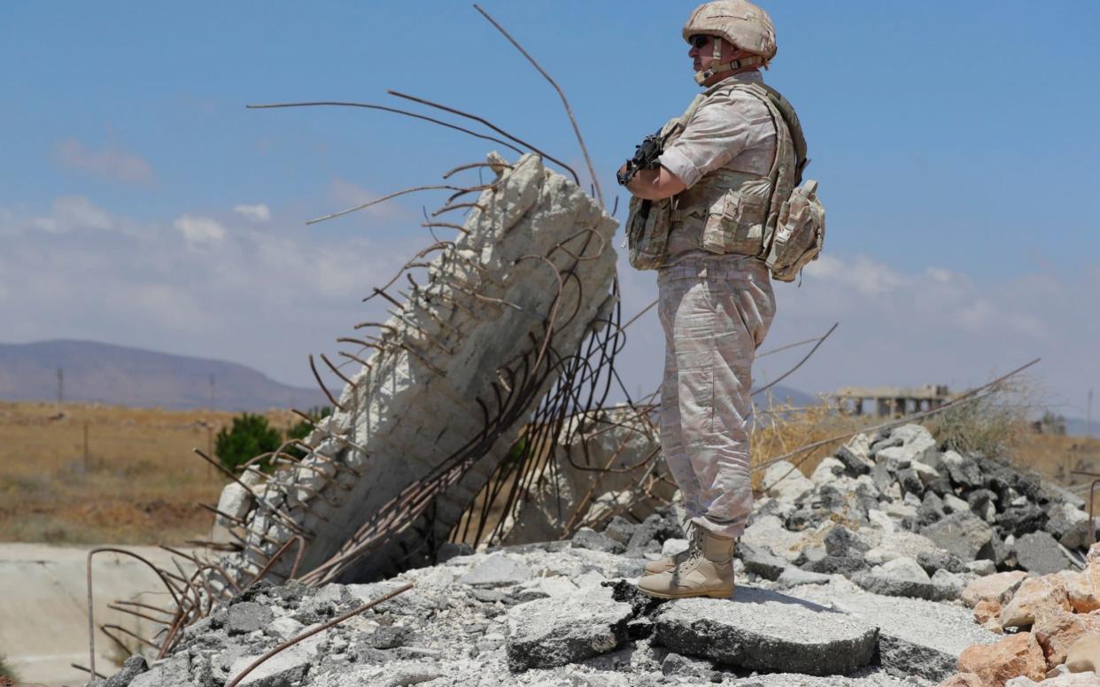 Russian military police officer stands guard near the town of Alhureyeh, Syria - AP