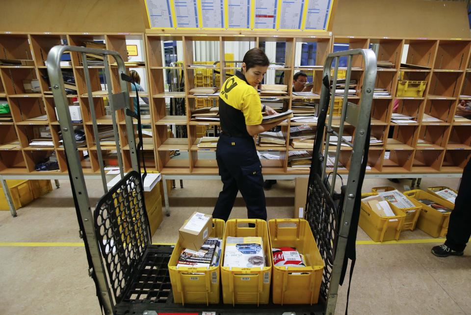 A postwoman of the German postal and logistics group Deutsche Post sorts mail at a sorting office in Berlin's Mitte district, December 4, 2013. Deutsche Post, the world's number one postal and logistics group, transported around 18 billion letters in 2012. REUTERS/Fabrizio Bensch (GERMANY - Tags: BUSINESS EMPLOYMENT)