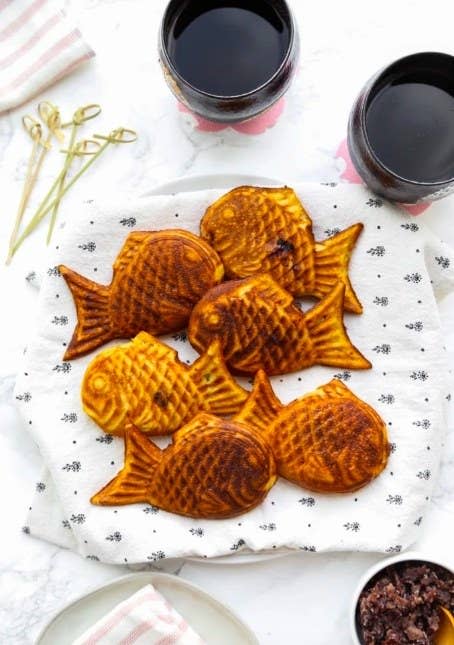 Group of Taiyaki pastries laying on a patterned cloth on top of a plate.