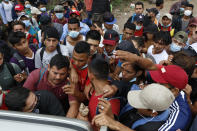 Migrants hoping to reach the U.S. border crowd in to receive food from volunteers, in Chiquimula, Guatemala, Saturday, Jan. 16, 2021. Honduran migrants pushed their way into Guatemala Friday night without registering, a portion of a larger migrant caravan that had left the Honduran city of San Pedro Sula before dawn, Guatemalan authorities said. (AP Photo/Delmer Martinez)