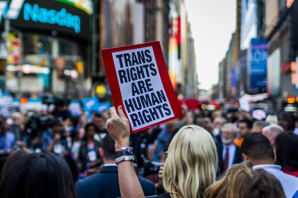 A person holds up a sign on a crowded sidewalk reading 