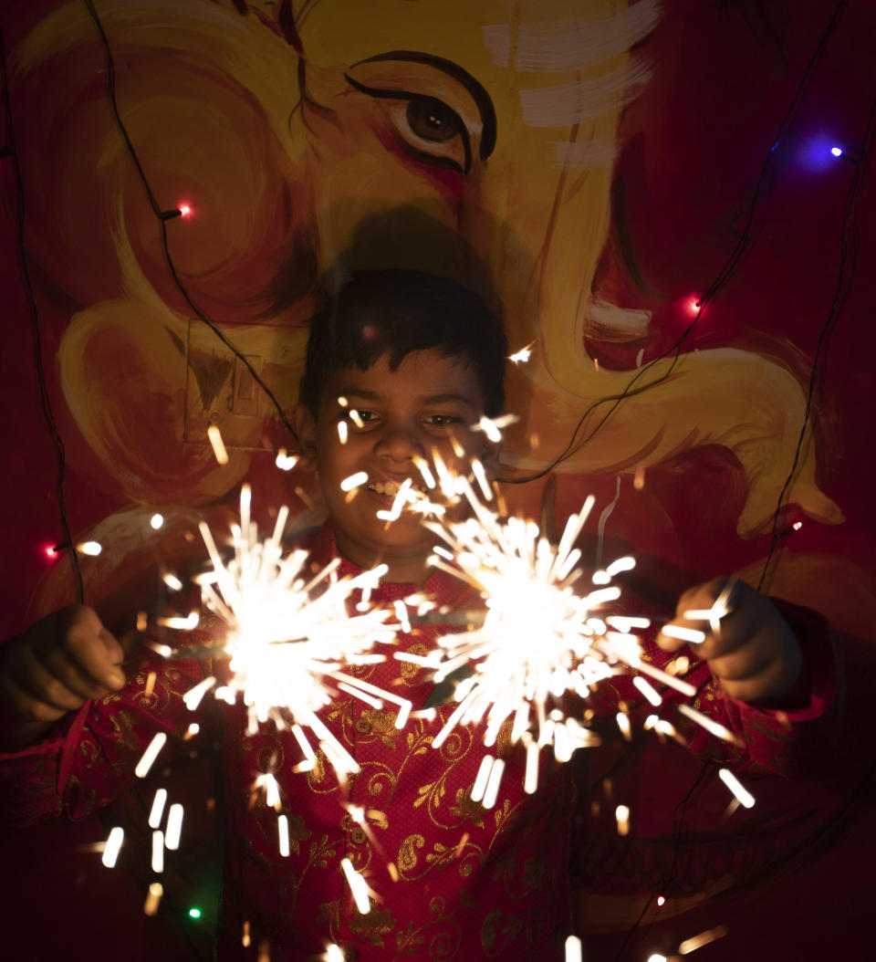 A child plays with fireworks during Diwali, the Hindu festival of lights, in Prayagraj, India, Saturday, Nov. 14, 2020. Hindus across the country are celebrating Diwali where people decorate their homes with lights and burst fireworks. (AP Photo/Rajesh Kumar Singh)