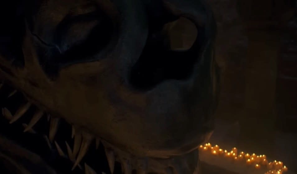 Balerion's skull surrounded by candles, with someone moving in the shadows