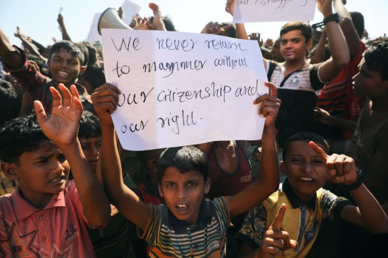 A boy holds a placard as hundreds of Rohingya refugees protest against their repatriation at the Unchiprang camp in Teknaf