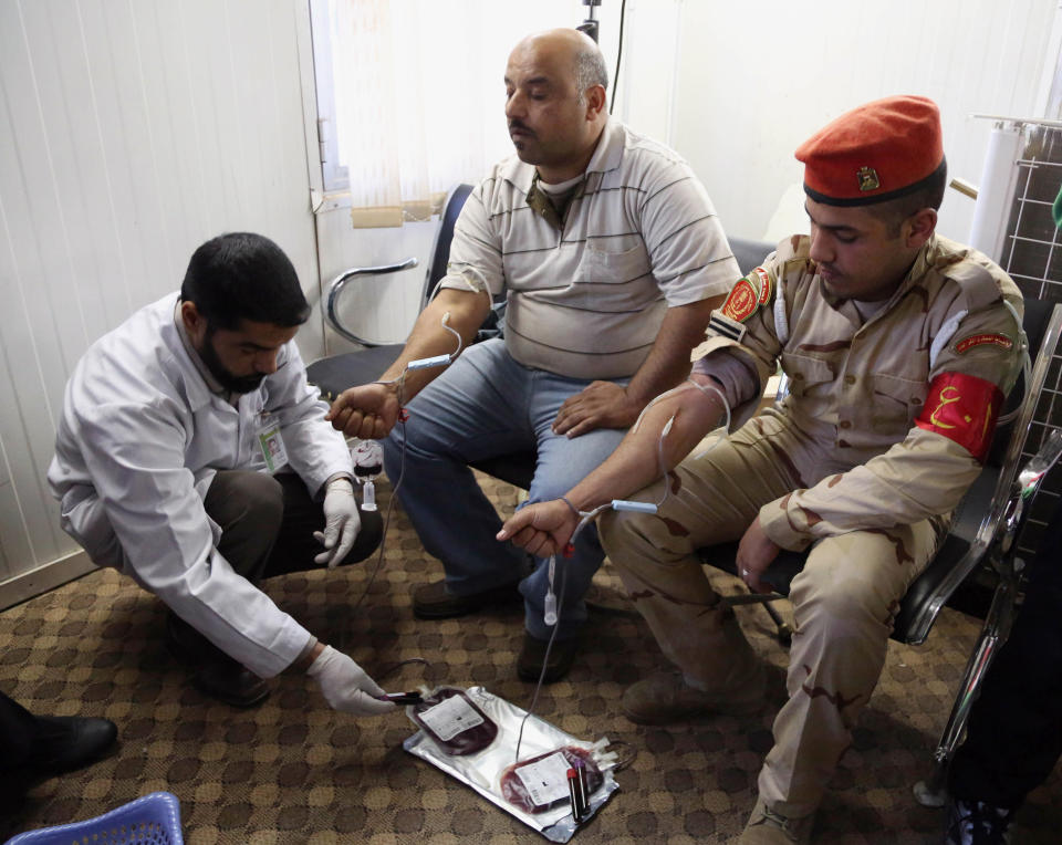 An Iraqi soldier and journalist donate blood for victims of military operations in Anbar Province at the journalists syndicate Baghdad, Iraq, Tuesday, Jan. 7, 2014. Iraqi security forces and allies from Sunni tribes have been battling militants to recapture two key cities in Iraq’s western Anbar province. Al-Qaida-linked group, known as the Islamic State in Iraq and the Levant, are controlling the center of Fallujah and part of Ramadi.(AP Photo/Karim Kadim)