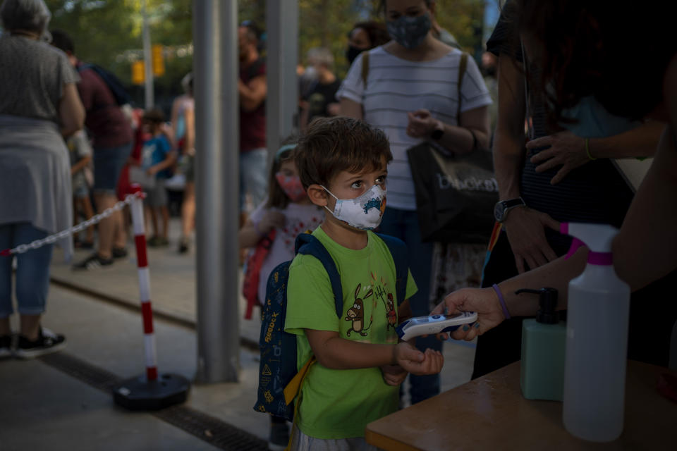 A student wearing a face mask to prevent the spread of coronavirus, has his temperature checked, prior to entering the school in Barcelona, Spain, Monday, Sept. 14, 2020. Students in Catalonia and Murcia returned to the classrooms for the first time since schools closed due to the coronavirus pandemic. (AP Photo/Emilio Morenatti)