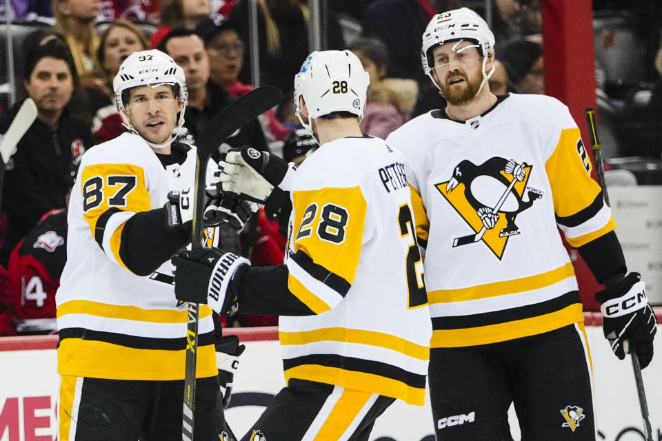 Pittsburgh Penguins' Sidney Crosby (87) celebrates with teammates Marcus Pettersson (28) Jeff Petry after scoring a goal during the first period of an NHL hockey game against the New Jersey Devils, Sunday, Jan. 22, 2023, in Newark, N.J. (AP Photo/Frank Franklin II)