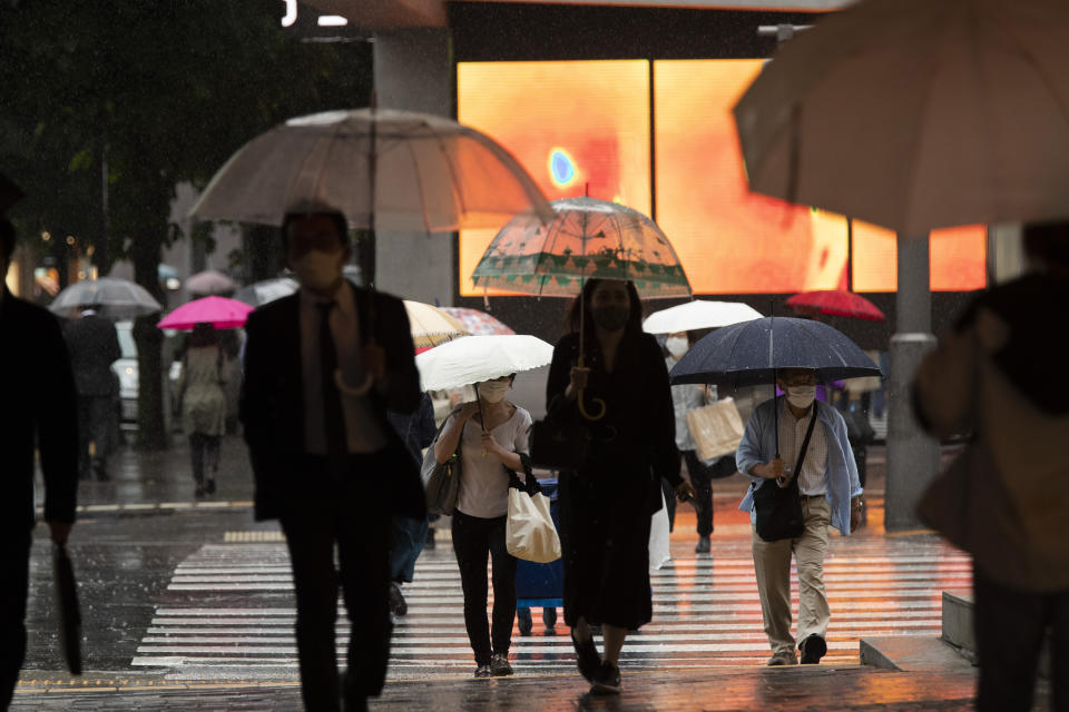 People wearing face masks walk across an intersection in the famed Ginza shopping area on a rainy day in Tokyo on Thursday, May 27, 2021. (AP Photo/Hiro Komae)