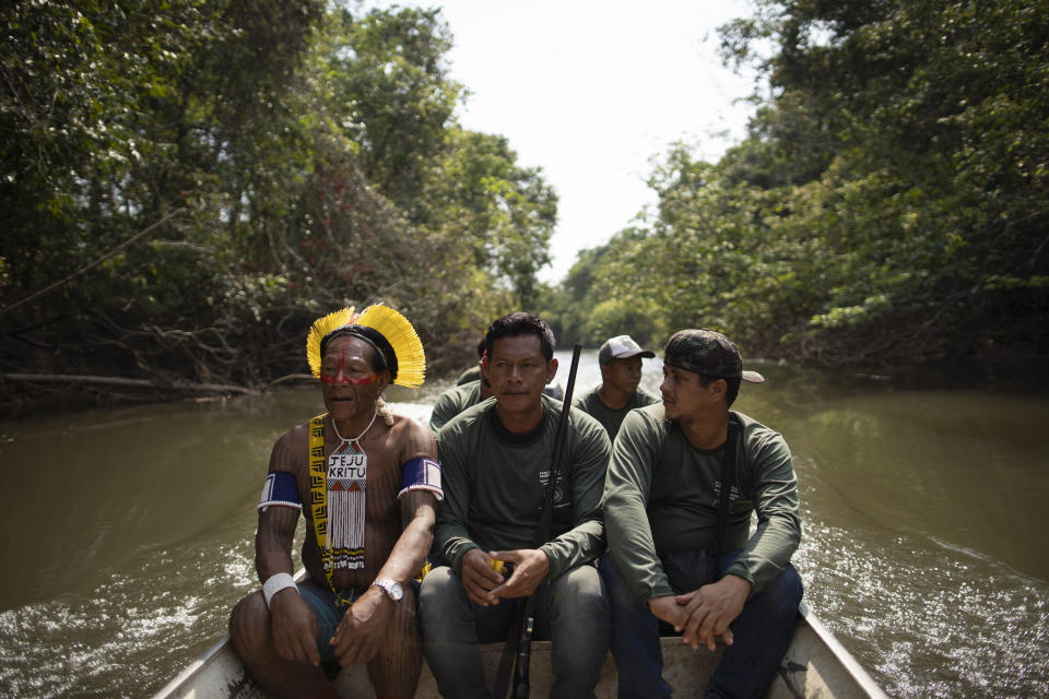 Krimej village indigenous Chief Kadjyre Kayapo, of the Kayapo indigenous community, sits next to his son Monhire Menkragnotire, center holding a rifle, on the Pitchacha River as they advance to a bridge constructed by loggers as they survey Menkragnotire indigenous land in Altamira, Brazil, Saturday, Aug. 31, 2019. Much of the deforestation in the Brazilian Amazon is done illegally -- land grabbers burn areas to clear land for agriculture and loggers encroach on national forests and indigenous reserves, and Kayapo says that he does not want loggers and prospectors on his land. (AP Photo/Leo Correa)