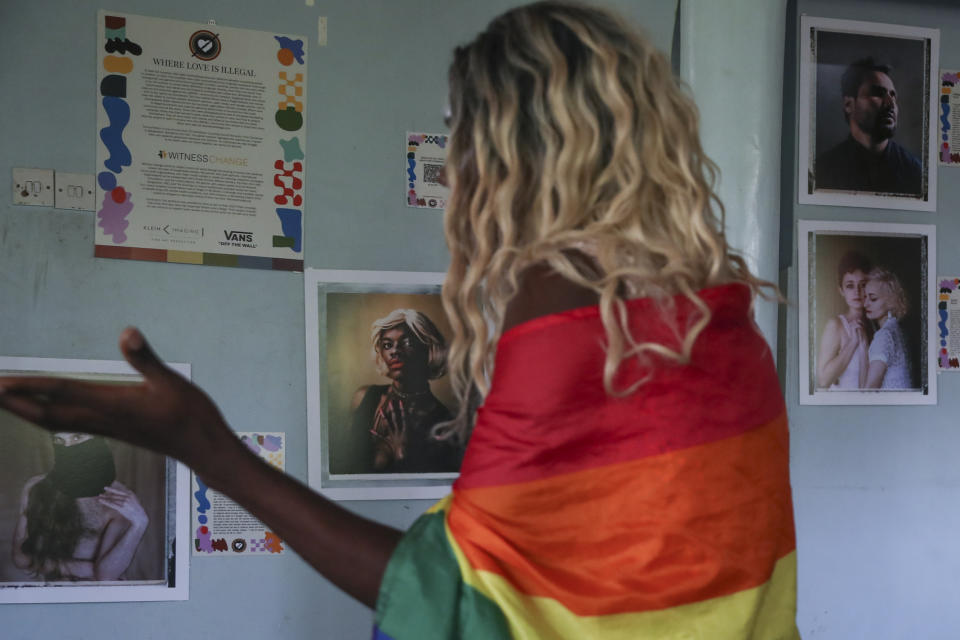 Ugandan transgender woman Pretty Peter who fled her home and country in 2019, and wished to be identified by her chosen name out of concern for her safety, looks at portraits on the wall from a global project called "Where Love is Illegal", at the safe house where she now lives in Nairobi, the capital of neighboring Kenya Thursday, June 1, 2023. She says frightened members of the Ugandan LGBTQ+ community are searching for a way to get out of the country and some have stayed indoors since new anti-gay legislation was signed on Monday. (AP Photo/Brian Inganga)