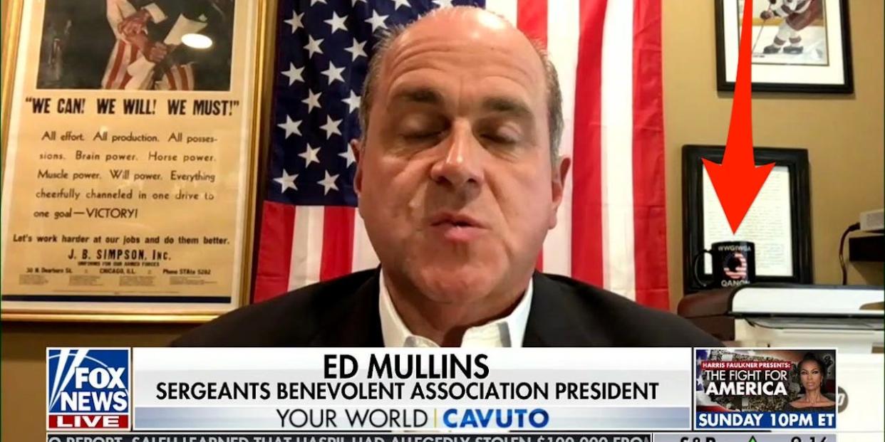 NYPD sergeants union chief Ed Mullins displays a QAnon mug while being interviewed on Fox News.