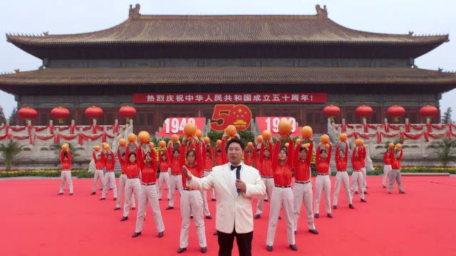 Chinese workers from the Capital Steel Plant hold their helmets aloft as they perform in front of the Forbidden City in 1999.