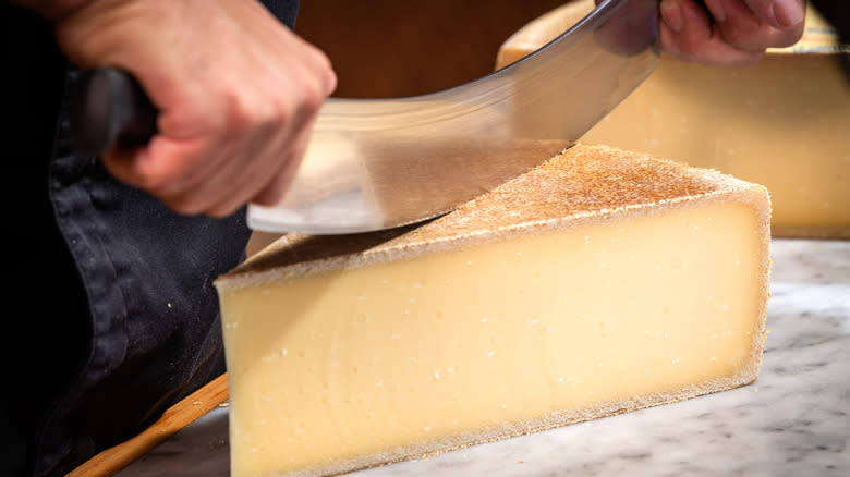 Person cutting Gruyére cheese