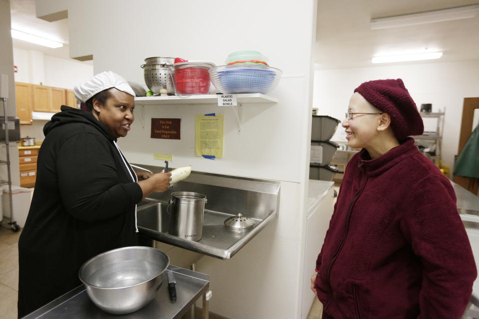 Guest Letisa Isler, left, speaks with Thubten Damcho, a fully ordained Buddhist nun, while preparing lunch in the kitchen at Sravasti Abbey, Thursday, Nov. 18, 2021, in Newport, Wash. (AP Photo/Young Kwak)