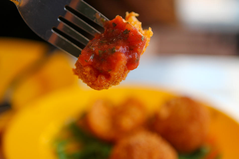 Close up of half-cut Arancini dipped in sauce