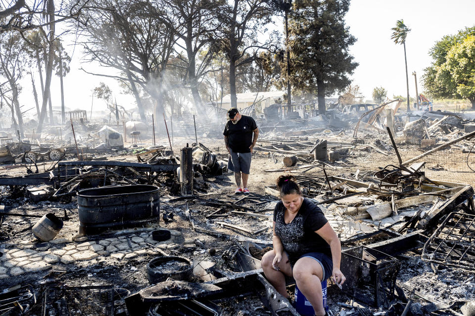 Kim Corgiat helps boyfriend James Grooms sift through the remains of his home at the Rancho Marina Mobile Home & RV Park following the Brannan Fire in Sacramento County, Calif., Tuesday, Oct. 12, 2021. Fueled by dry, strong winds, the blaze leveled dozens of residences on Brannan Island on Monday afternoon. (AP Photo/Noah Berger)