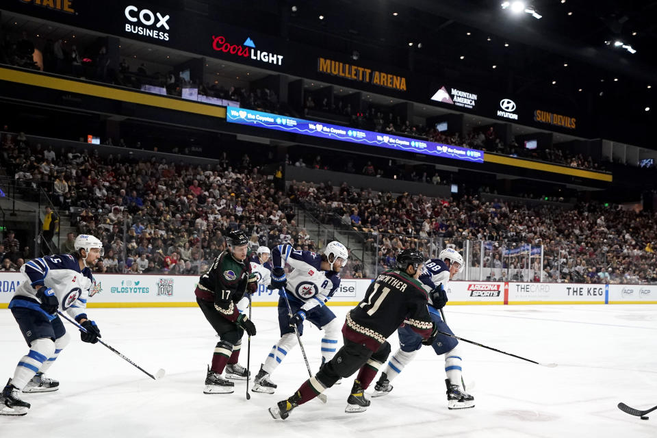 FILE - Winnipeg Jets defenseman Brenden Dillon (5), Arizona Coyotes center Nick Bjugstad (17), Jets center Adam Lowry (17), Coyotes right wing Dylan Guenther (11), and Jets defenseman Nate Schmidt (88) look for the puck during the first period of an NHL hockey game at Mullett Arena in Tempe, Ariz., Friday, Oct. 28, 2022. Arizona Coyotes fans always had hope the franchise would find stability in the desert despite numerous difficulties. Now that the Coyotes are moving to Salt Lake City, they're taking those hopes with them. (AP Photo/Ross D. Franklin, File)